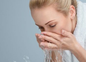 Young woman washing her face and hands with clean water in the morning