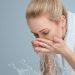 Young woman washing her face and hands with clean water in the morning