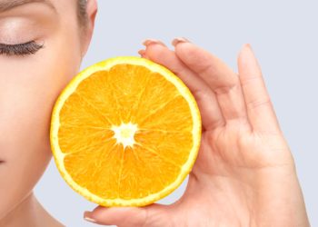 portrait of young woman with eyes closed holding orange and showing and promoting a healthy eating and a healty lifestyle.